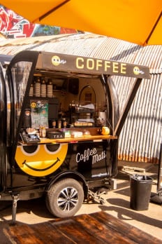 Een koffiekar met een smiley onder een parasol