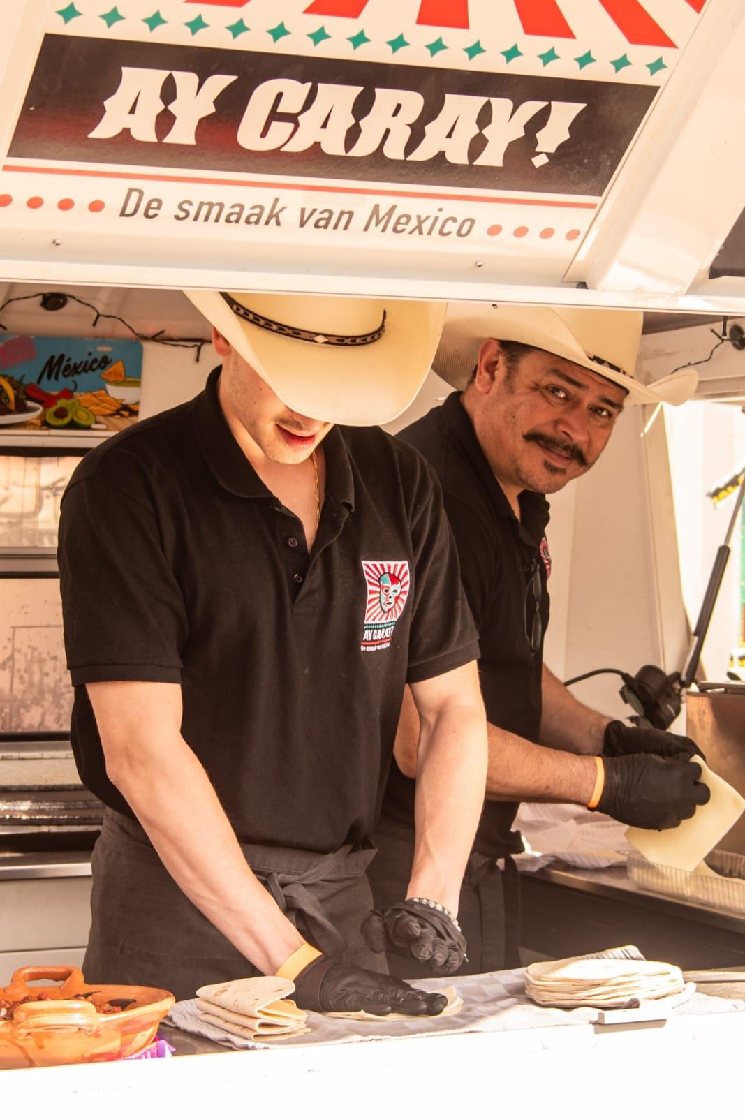 Twee koks met cowboyhoed maken tortilla's in de foodtruck van Ay Caray